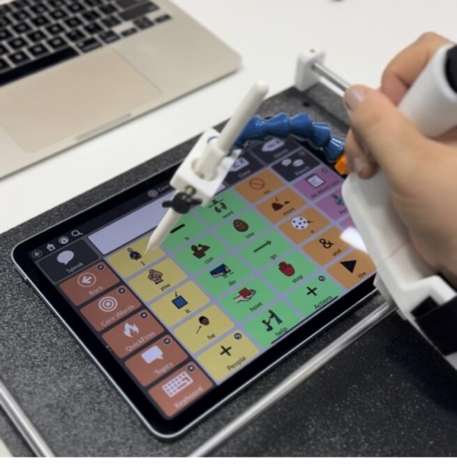 The Guided Hands assistive technology is being used to select and word on a word board. 
